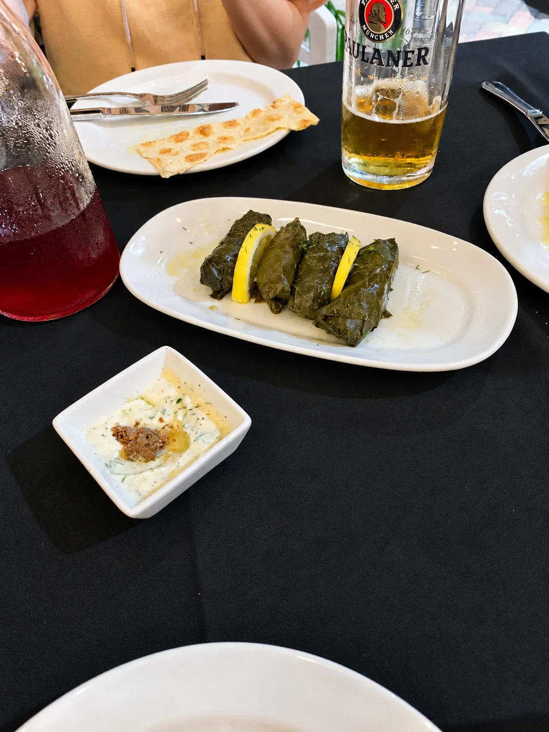 Grape-leaf tolma with lemon wedges and a separate bowl of yogurt sauce