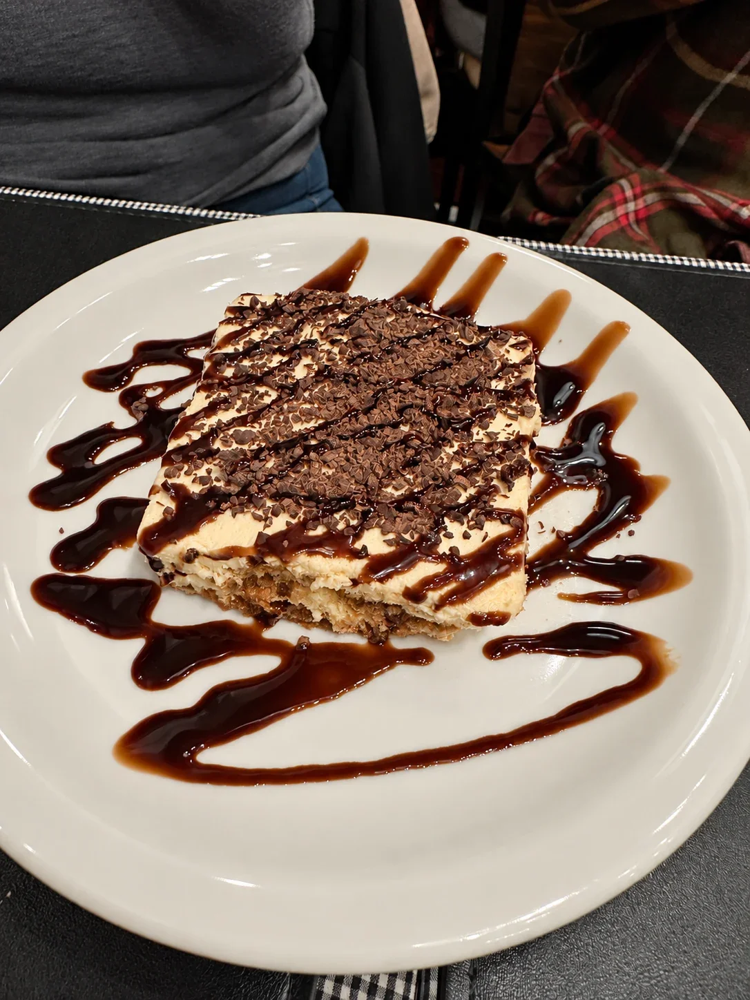 A square slice of tiramisu topped with chocolate shavings at Bodegón Núñez