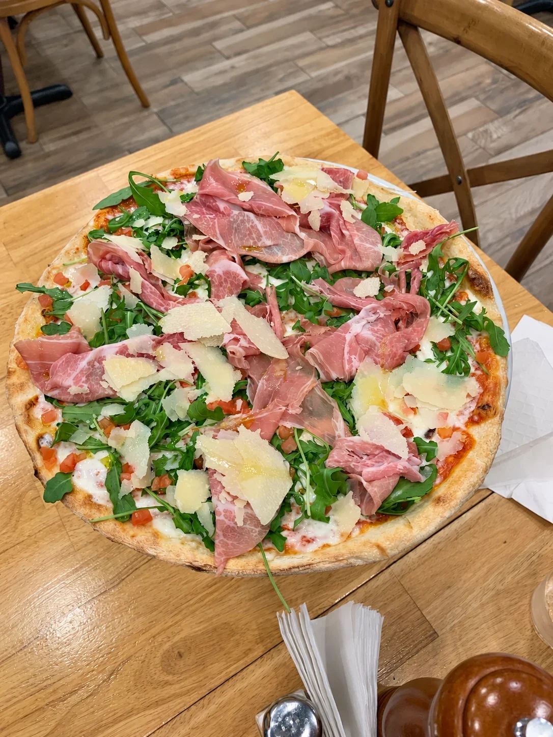 A Marco pizza topped with arugula, tomato, cheese shavings and added prosciutto at Mister O1