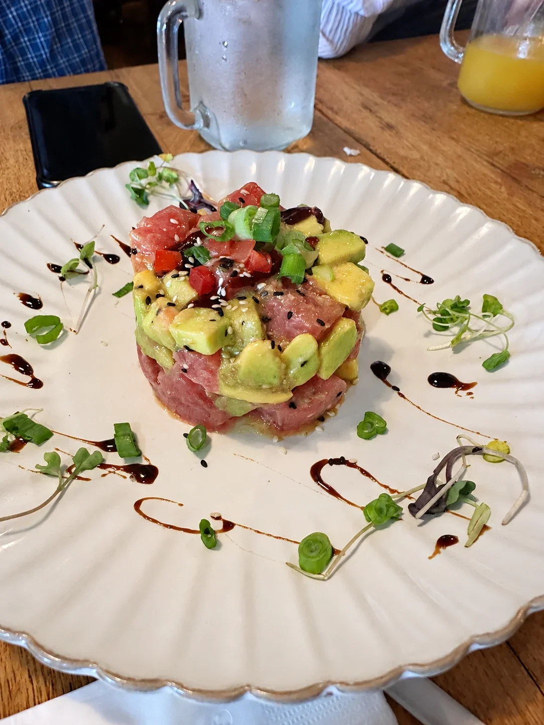 Diced tuna and avocado formed into a tower, with sesame seeds and sauce on a white plate at Piruw Grill