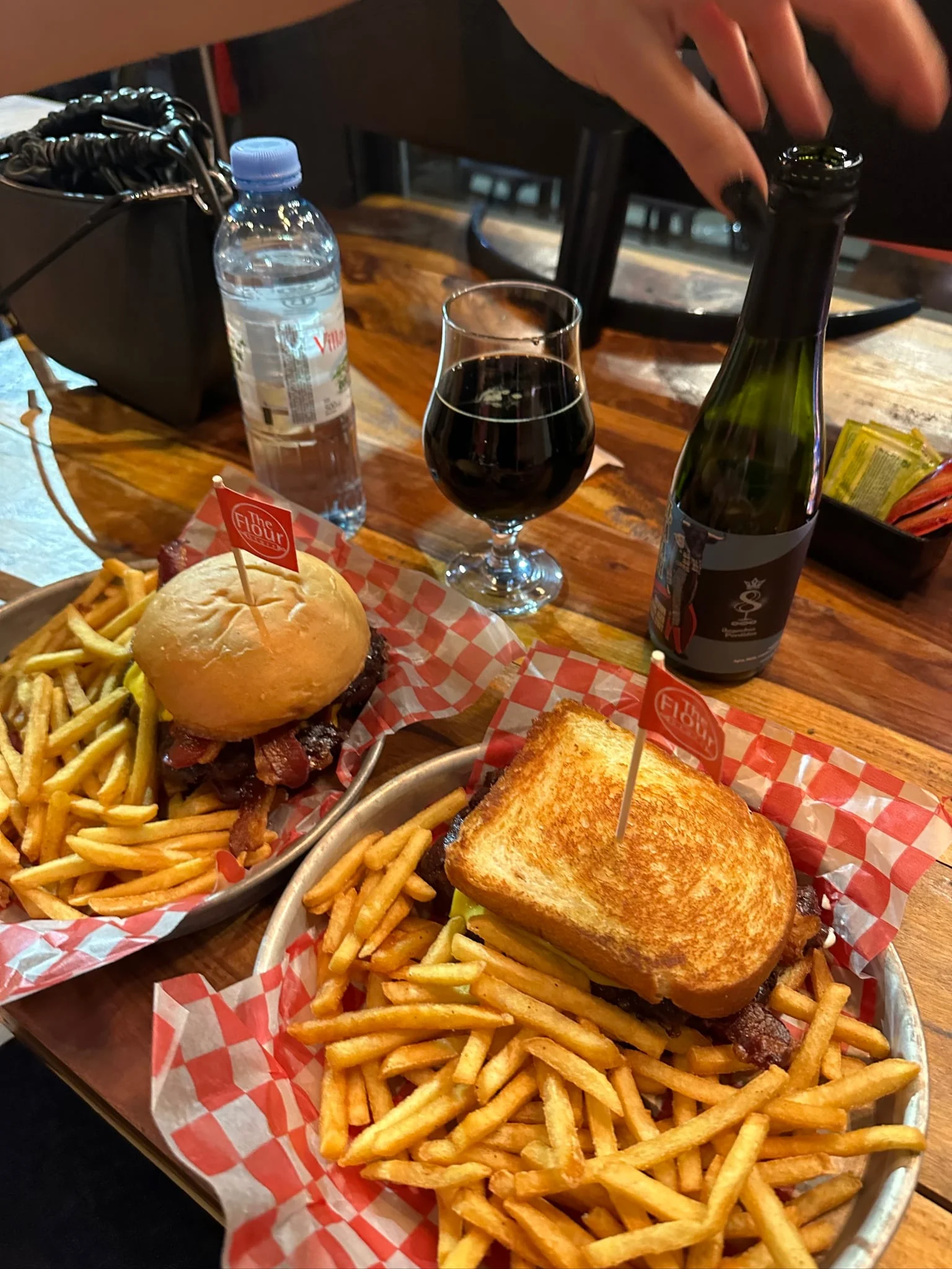 A round-bun burger and a patty melt with fries on two trays at The Flour Store in Almagro